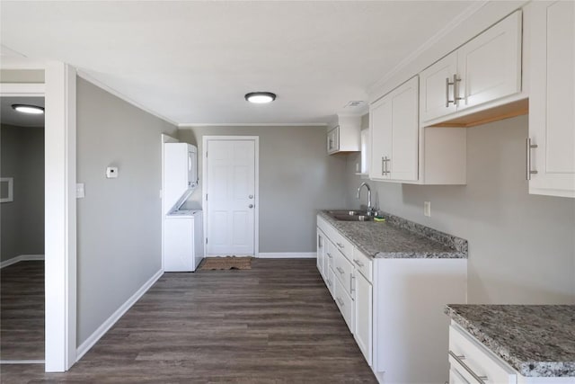 kitchen with a sink, white cabinetry, stacked washer / drying machine, ornamental molding, and dark wood-style floors