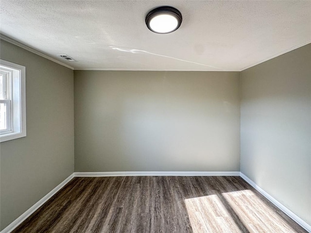 empty room featuring dark wood-style floors, visible vents, a textured ceiling, and baseboards