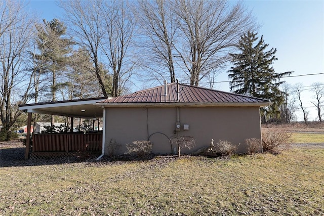 view of side of property featuring metal roof, a yard, and stucco siding