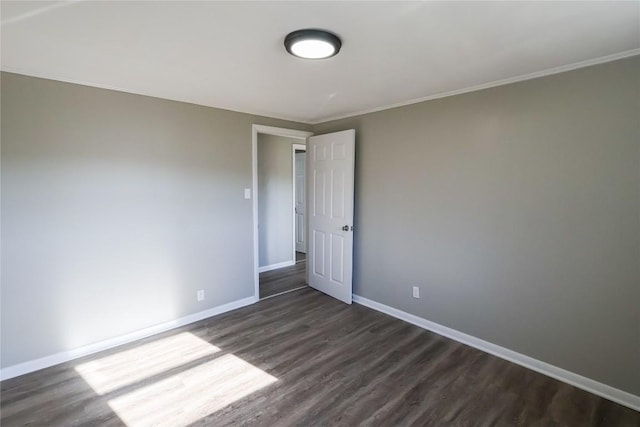 empty room featuring baseboards, dark wood finished floors, and ornamental molding