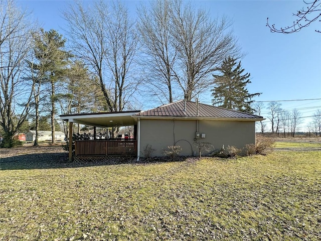 view of side of property with a yard, a standing seam roof, metal roof, and stucco siding