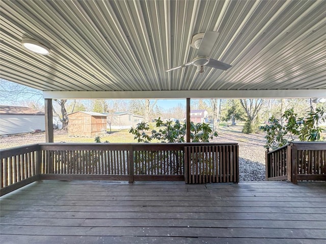 deck featuring ceiling fan, an outdoor structure, and a shed