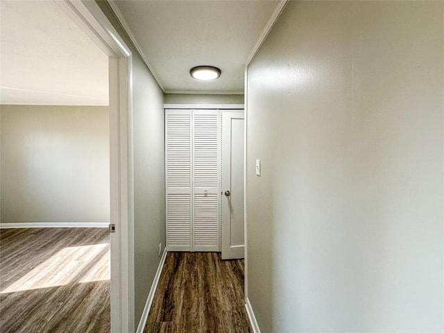 hallway featuring dark wood-style floors, baseboards, and ornamental molding