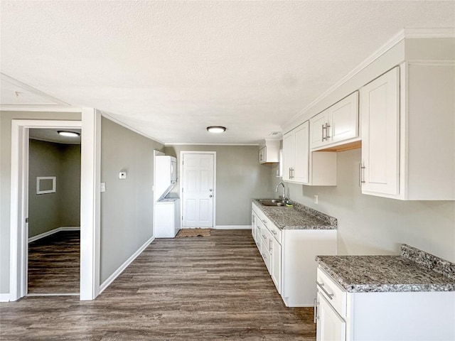 kitchen featuring white cabinets, dark wood-style flooring, crown molding, a textured ceiling, and a sink