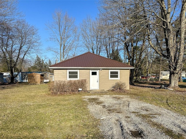 view of front of property with driveway, concrete block siding, metal roof, and a front yard