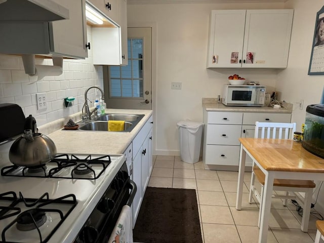 kitchen with backsplash, exhaust hood, white cabinets, sink, and light tile patterned floors