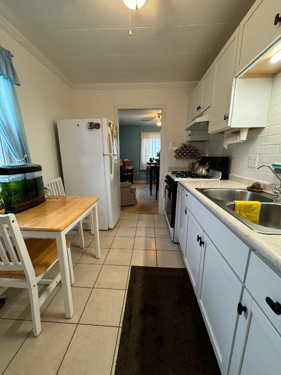 kitchen featuring light tile patterned floors, white appliances, white cabinetry, and ornamental molding