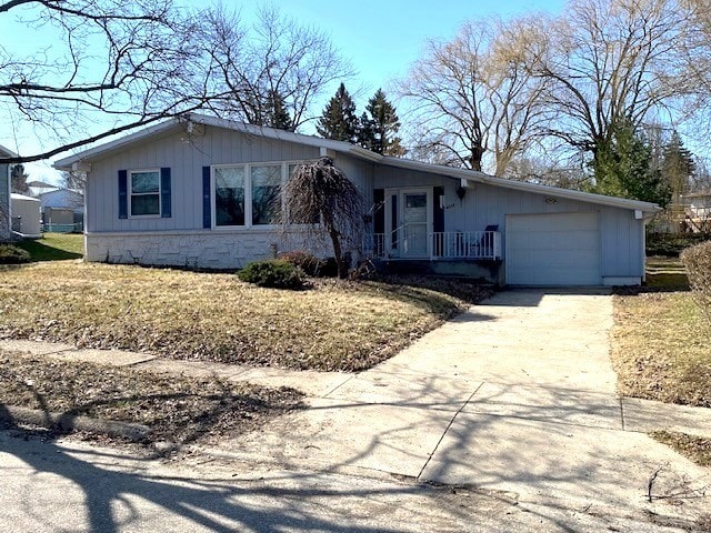 ranch-style house with stone siding, an attached garage, and driveway