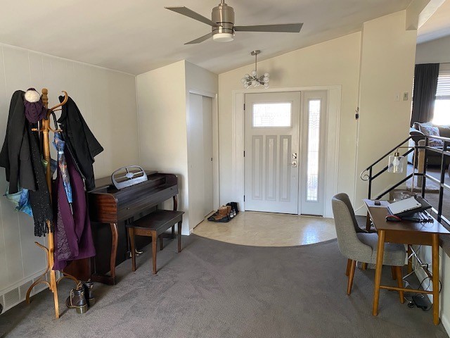 carpeted foyer with lofted ceiling and a ceiling fan