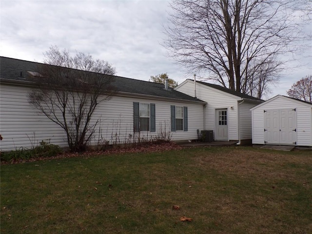 rear view of property with a lawn, a storage shed, and central AC