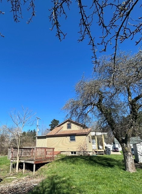 back of house featuring a lawn and a deck