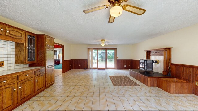 8410 Windsor Beach Ct, Erie, PA 16511 - kitchen with a wainscoted wall, ceiling fan, a textured ceiling, wooden walls, and a wood stove
