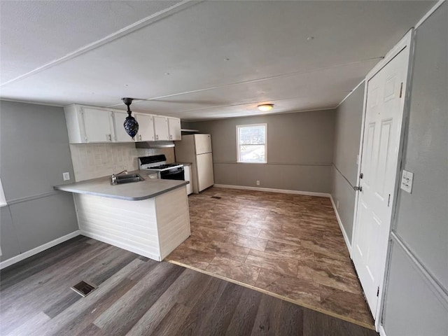 kitchen with decorative backsplash, dark wood-type flooring, white cabinets, white appliances, and a peninsula