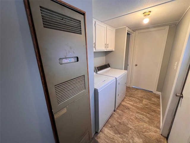 washroom with cabinet space, washing machine and dryer, and a heating unit