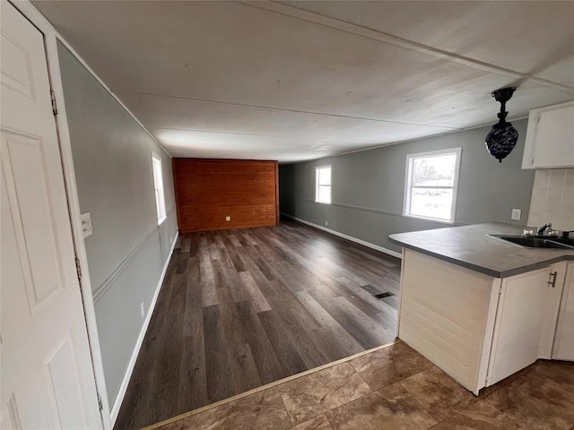 kitchen with a sink, white cabinetry, open floor plan, dark wood-style floors, and dark countertops