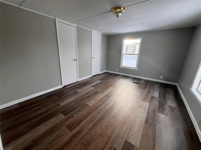 unfurnished bedroom featuring dark wood-style floors, visible vents, and baseboards