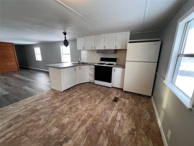 kitchen with a peninsula, white cabinets, freestanding refrigerator, gas stove, and pendant lighting