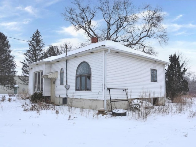 view of snow covered exterior with a chimney