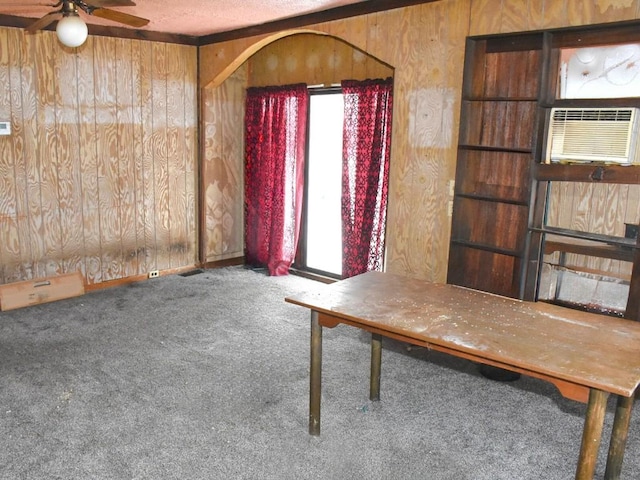 unfurnished dining area featuring carpet floors, wood walls, and a textured ceiling