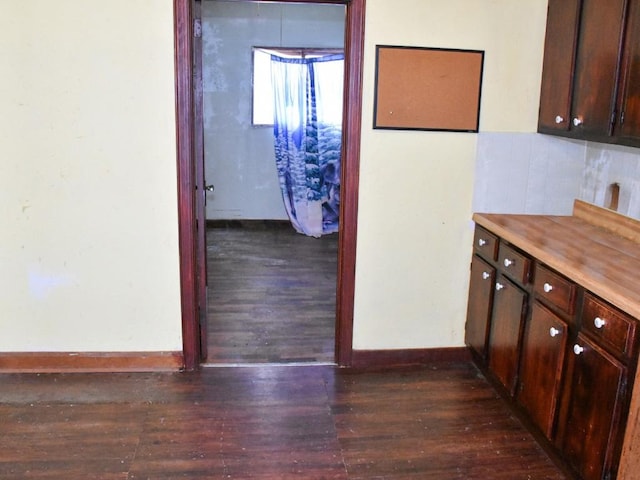 corridor featuring dark wood-style floors and baseboards