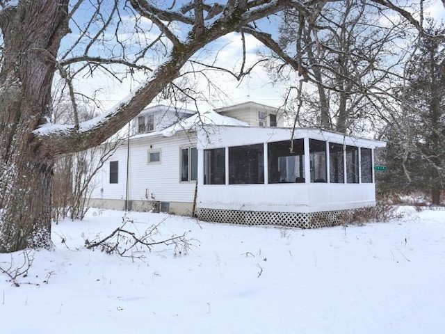 snow covered house featuring a sunroom