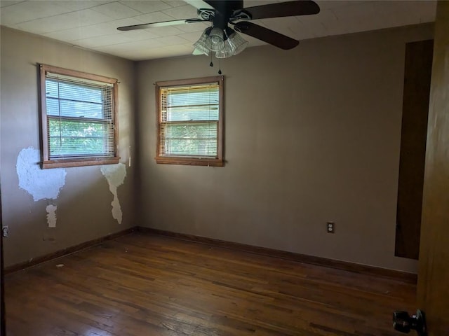 empty room with dark hardwood / wood-style floors, ceiling fan, and a healthy amount of sunlight