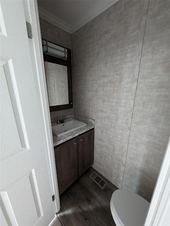 bathroom featuring vanity, crown molding, hardwood / wood-style flooring, toilet, and tile walls