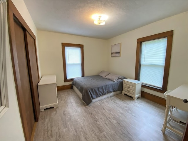 bedroom with a closet, light hardwood / wood-style floors, and a textured ceiling