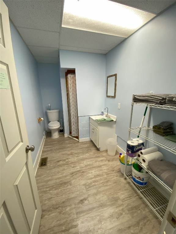 bathroom with vanity, hardwood / wood-style floors, a paneled ceiling, and toilet