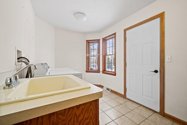 laundry area with light tile patterned floors, washer and dryer, and sink