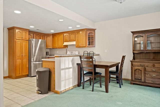 kitchen with light carpet, a breakfast bar, kitchen peninsula, and stainless steel fridge