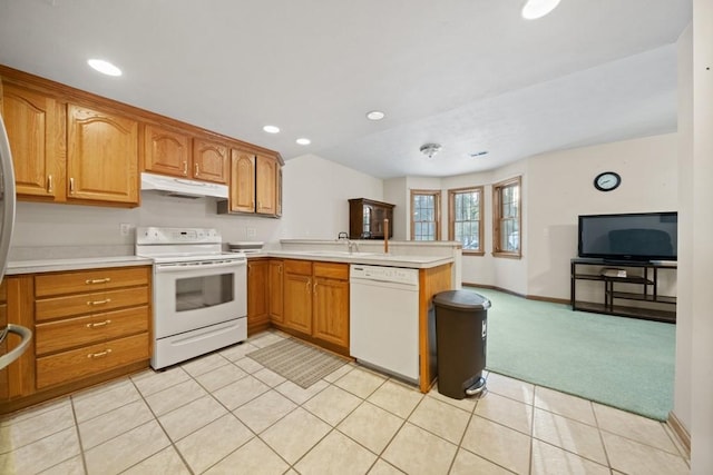 kitchen with sink, white appliances, light carpet, and kitchen peninsula