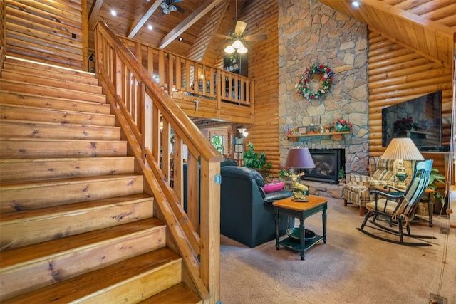 staircase featuring wooden ceiling, high vaulted ceiling, a stone fireplace, rustic walls, and beamed ceiling