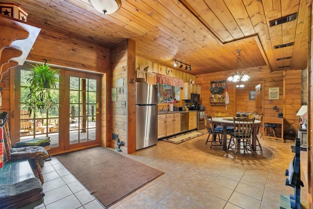 tiled dining room featuring a notable chandelier, wood ceiling, rail lighting, and wooden walls