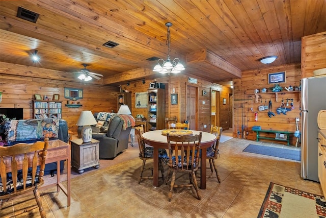 dining room with ceiling fan with notable chandelier, wood walls, light tile patterned flooring, and wood ceiling