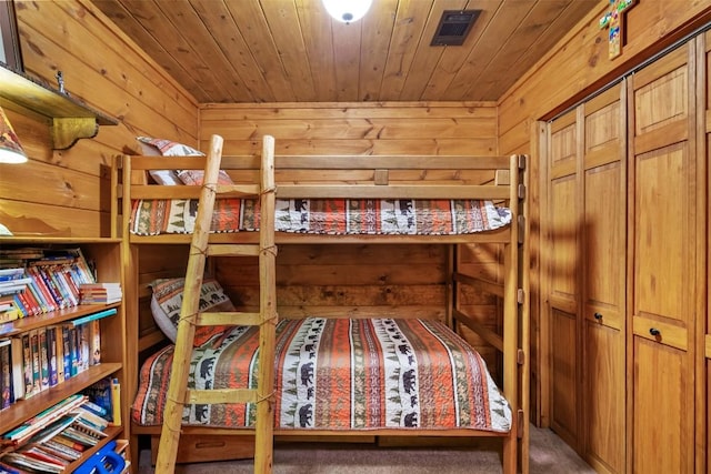 carpeted bedroom with a closet, wooden ceiling, and wood walls