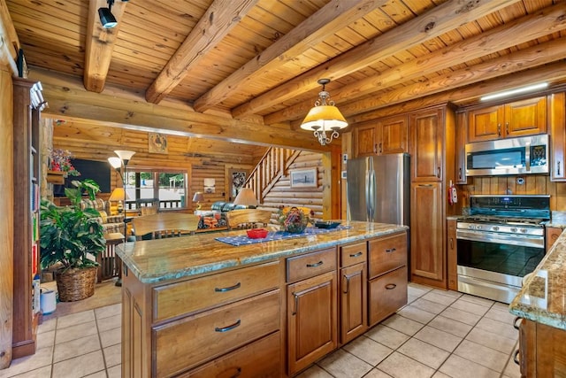 kitchen featuring light stone countertops, rustic walls, stainless steel appliances, decorative light fixtures, and a center island