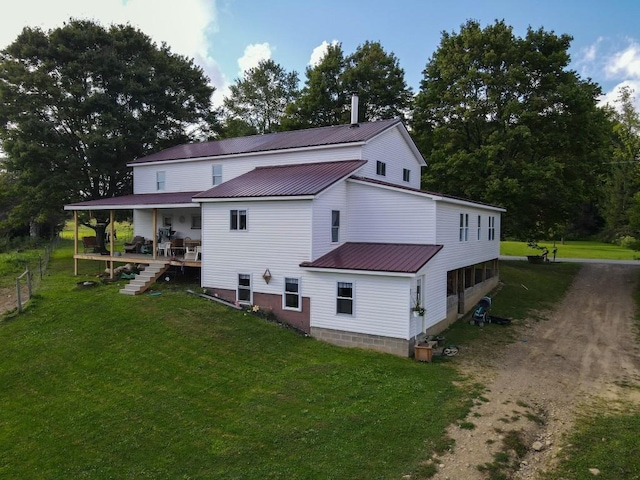 rear view of property featuring covered porch and a yard