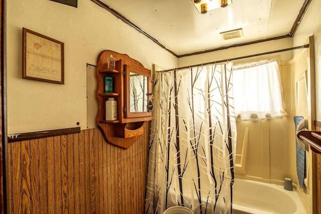 bathroom with shower / bath combo with shower curtain and wood walls