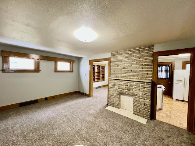 unfurnished living room featuring a stone fireplace, light carpet, and a textured ceiling