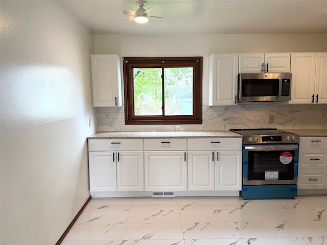 kitchen with appliances with stainless steel finishes, white cabinets, a ceiling fan, and marble finish floor