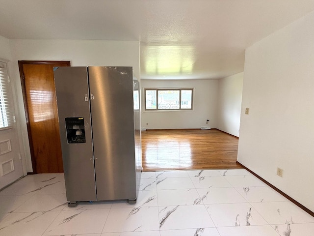 kitchen featuring stainless steel fridge, marble finish floor, and baseboards
