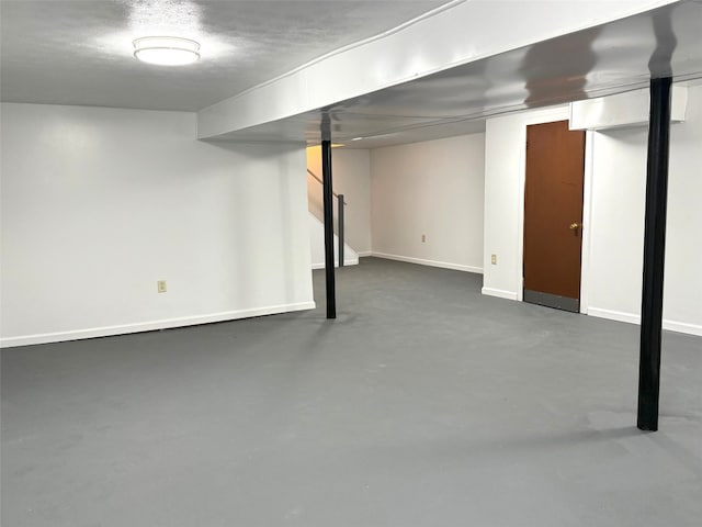 finished below grade area featuring a textured ceiling and baseboards