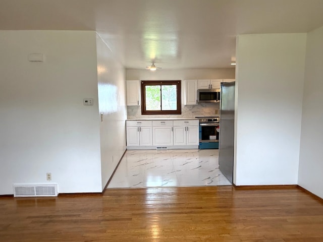 kitchen with visible vents, appliances with stainless steel finishes, tasteful backsplash, light countertops, and white cabinetry