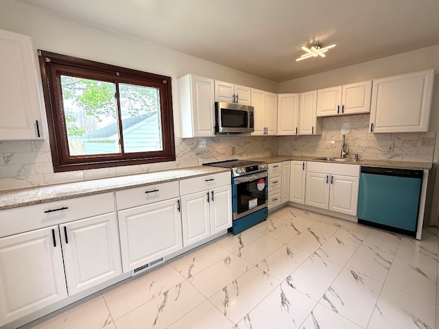 kitchen with white cabinets, a sink, marble finish floor, stainless steel appliances, and visible vents