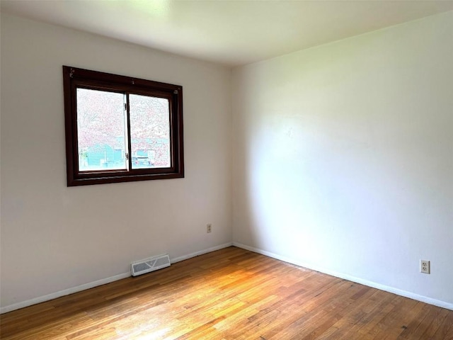 spare room featuring visible vents, light wood-style floors, and baseboards