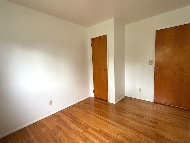 spare room with baseboards and wood finished floors