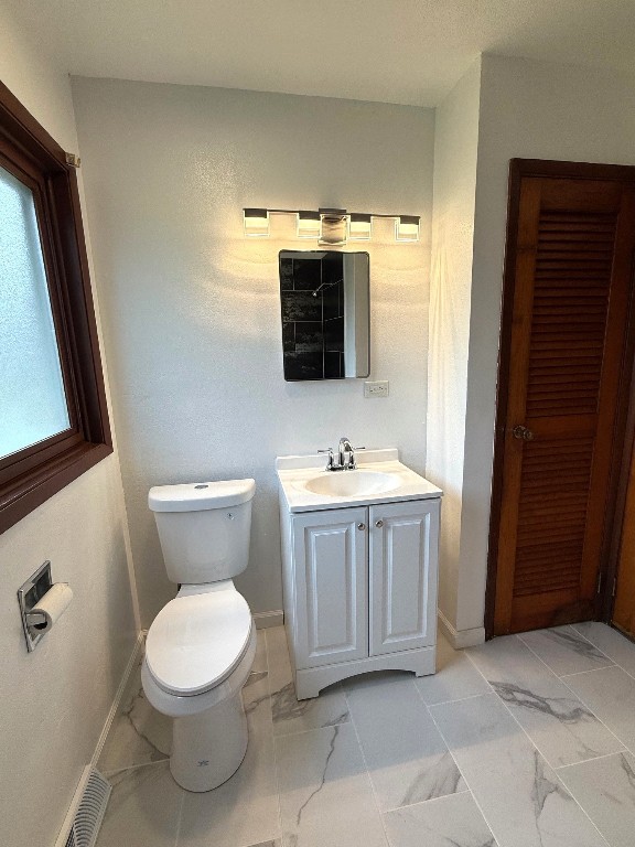 bathroom with toilet, baseboards, marble finish floor, and vanity