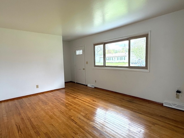 unfurnished room featuring baseboards, light wood-type flooring, and visible vents