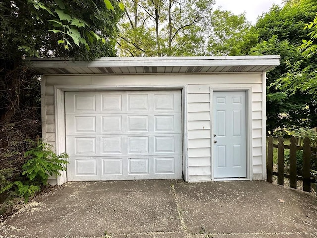 detached garage with concrete driveway and fence